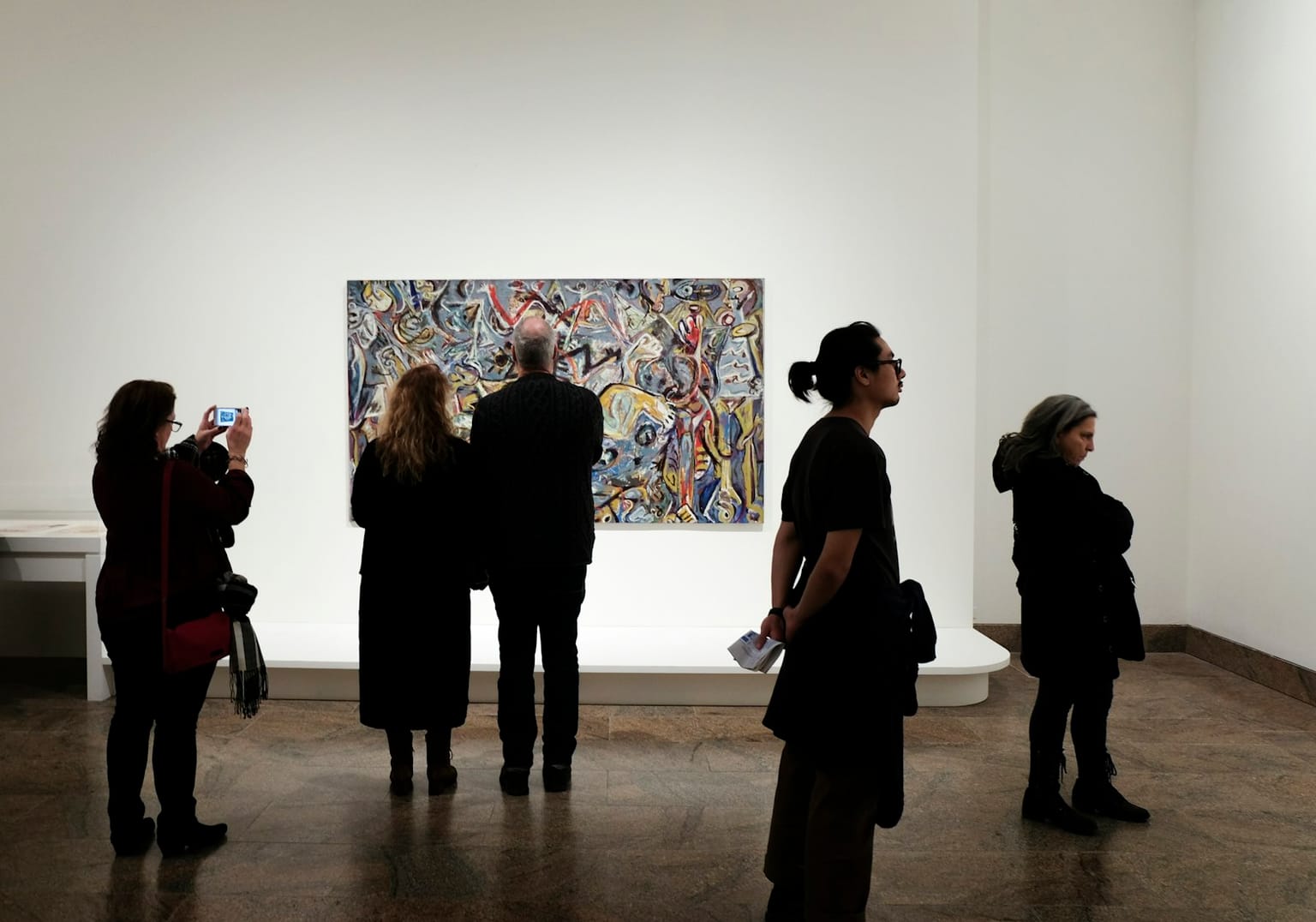 Menschen drängen sich in einer Galerie vor einem einzigen ausdrucksstarken Gemälde dicht zusammen.